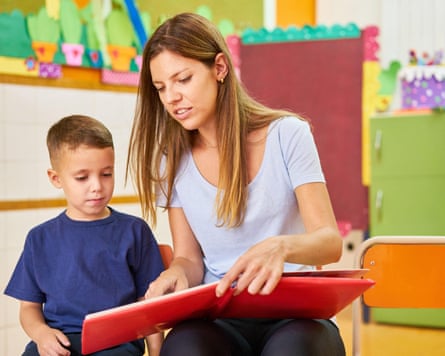 a nursery teacher reads to a child