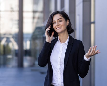 A young businesswoman talking on the street near an office building on a mobile phone