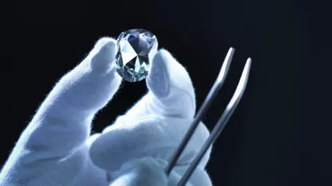 Getty Images A white-gloved hand holds a large diamond.