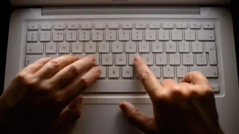 PA/ Dominic Lipinski Hands on a laptop keyboard.