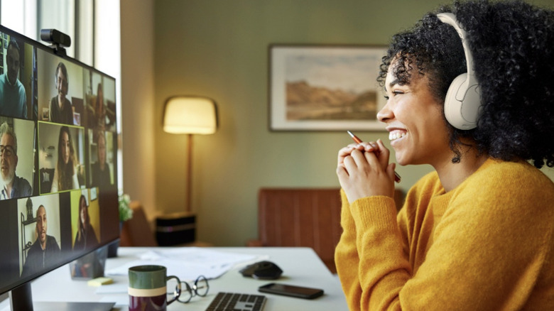 A woman on a video team call on her computer smiling while wearing the Belkin Soundform Isolate headphones.