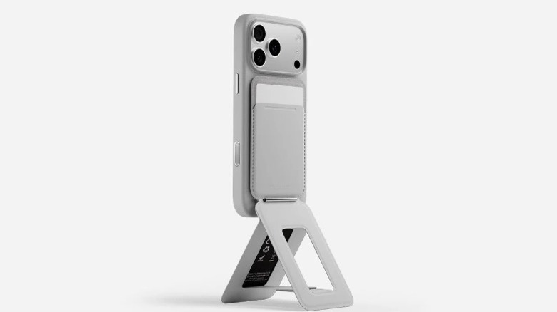 A product render of the Moft Trackable Tripod Wallet attached to the back of an iPhone via MagSafe.